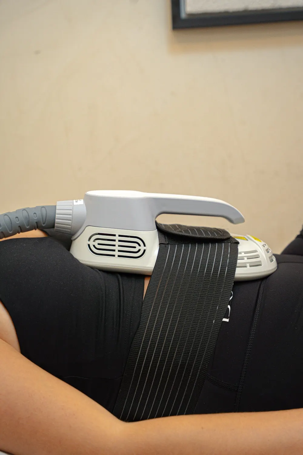 Applicateur Emsculpt sanglé sur le ventre